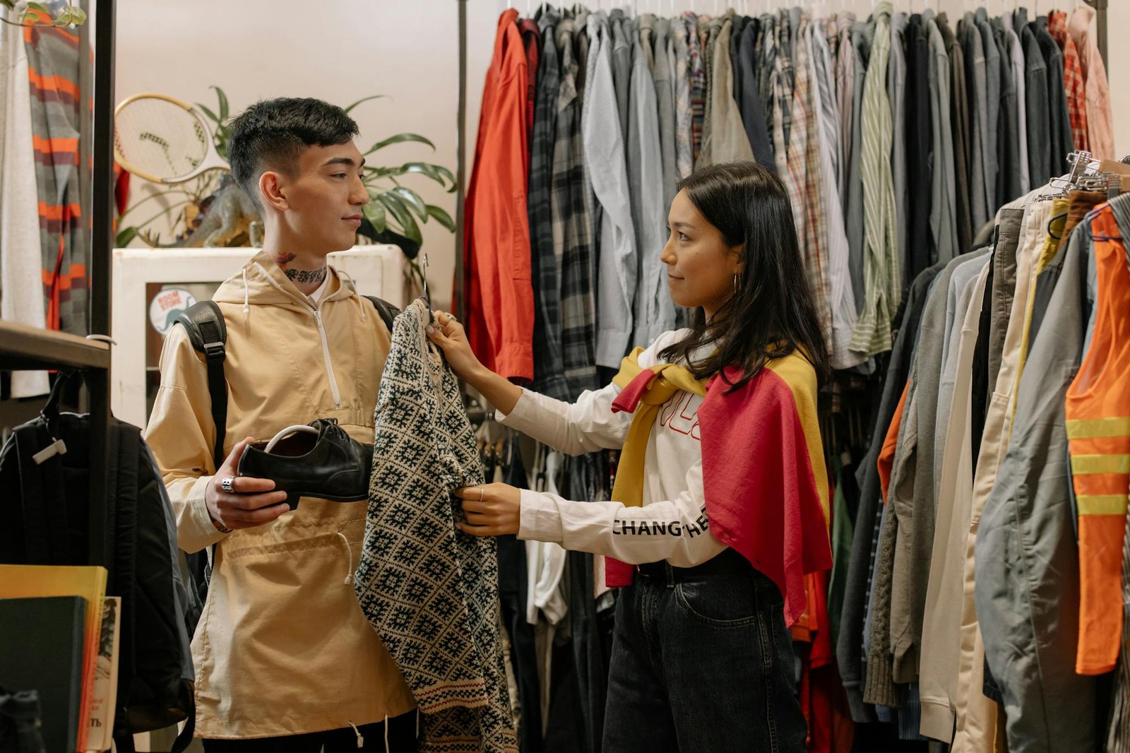 A young man and woman looking at clothes in a stylish boutique shop, exploring fashion options.