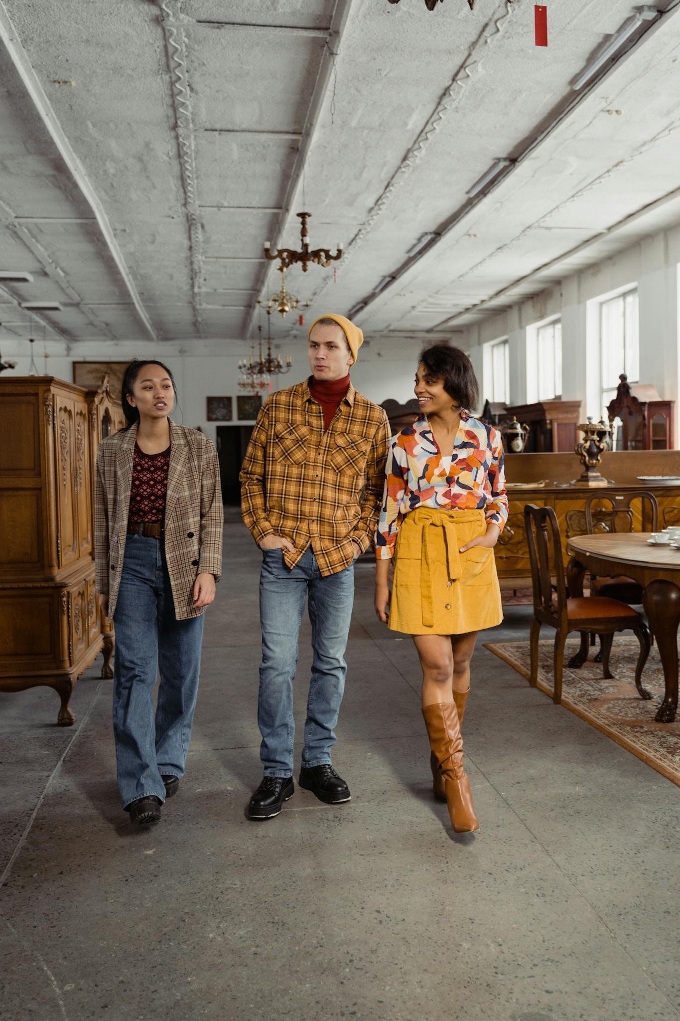 Diverse group of young adults exploring an antique store's interior, showcasing vintage furniture.
