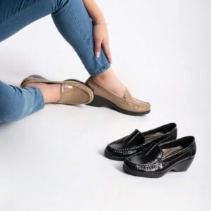 Elegant pair of beige and black moccasins in a studio setting with a model.